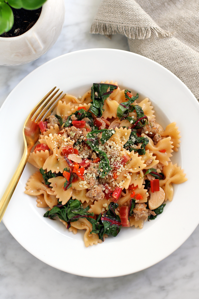 Close-up image of farfalle with sausage and chard.
