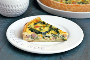 Image of a slice of spinach, ham and cheese quiche.