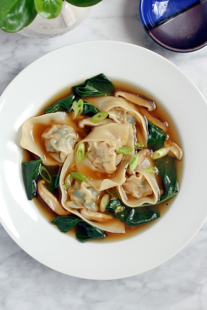 Close-up image of pork wonton soup with chard and shiitake mushrooms.