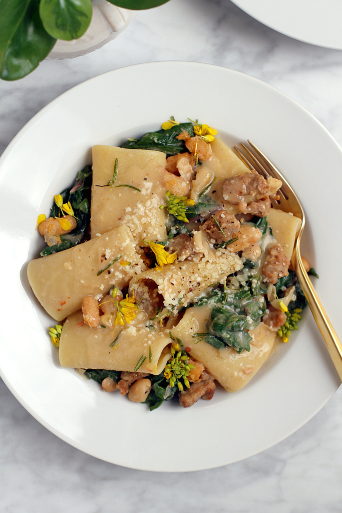 Close-up image of sausage, greens and beans pasta.