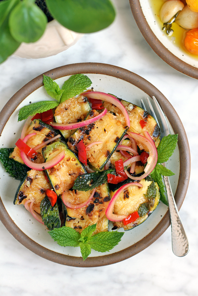 Close-up image of torn zucchini with mint and Calabrian chiles.