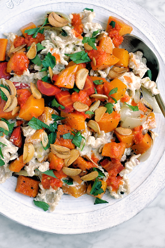 Close-up image of pasta with roasted butternut squash and carrots in warm yogurt sauce.