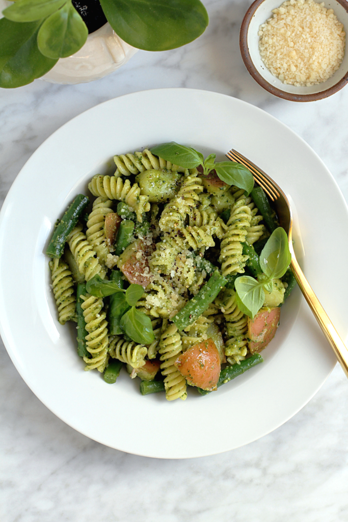 Close-up image of pasta, green beans and potatoes with pesto.