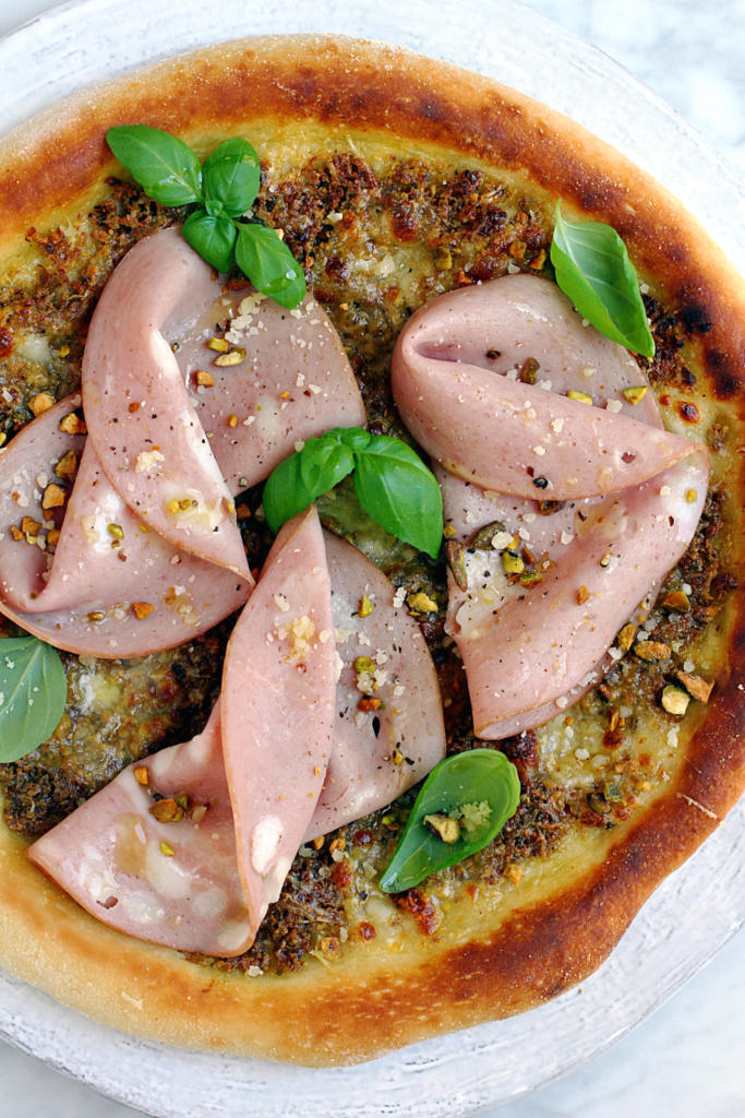 Close-up image of mortadella and pistachio pizza.