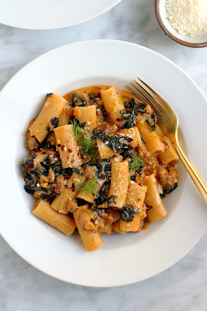 Close-up image of rigatoni with sausage and red kale.