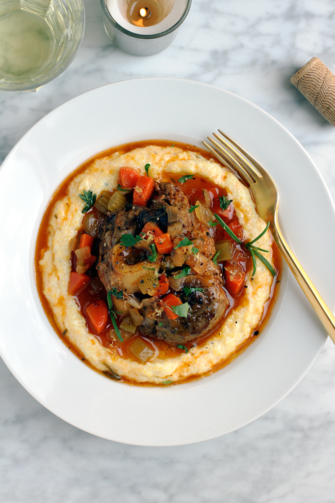 Close-up image of pork osso buco with creamy polenta.