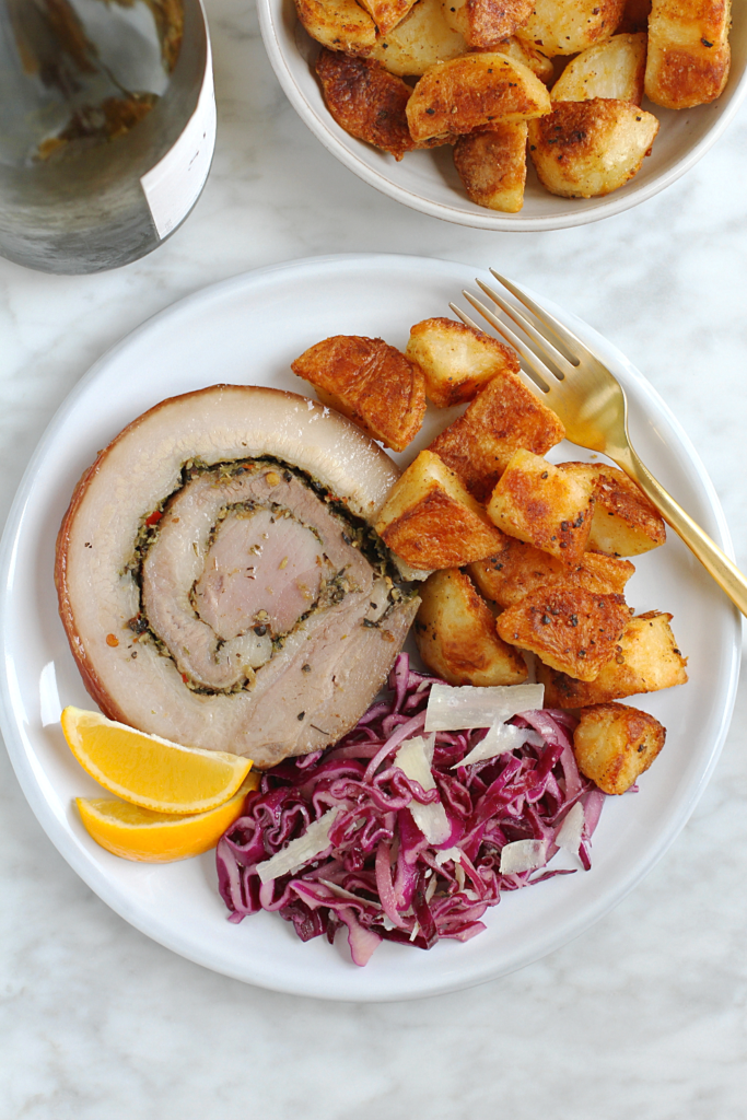 Close-up image of crispy roasted potatoes with porchetta.