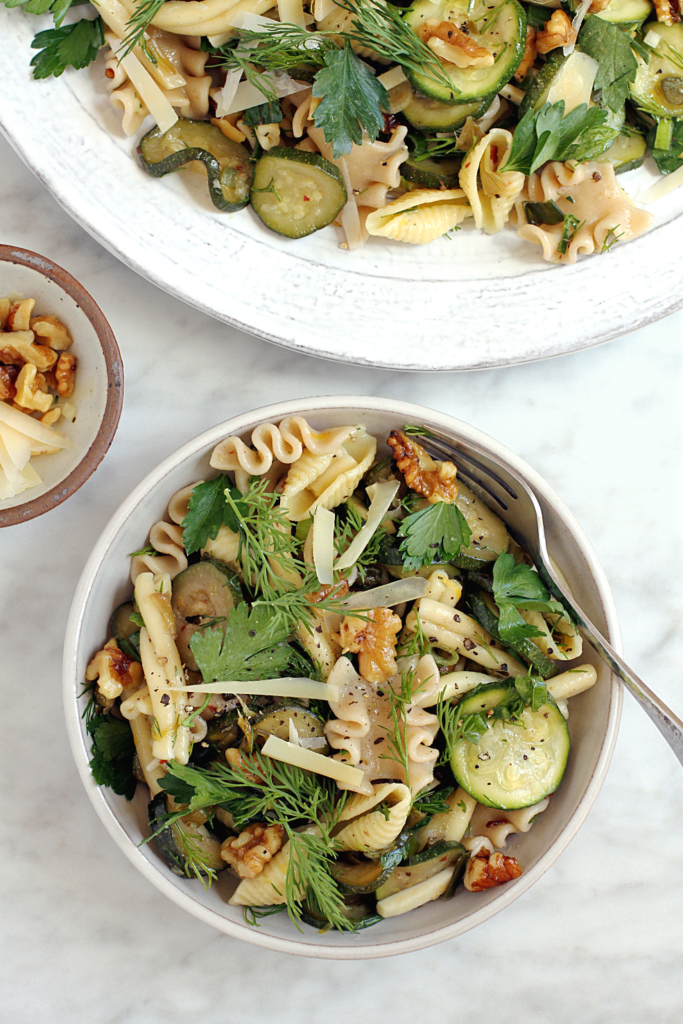Close-up image of pasta salad with zucchini and sizzled scallions.