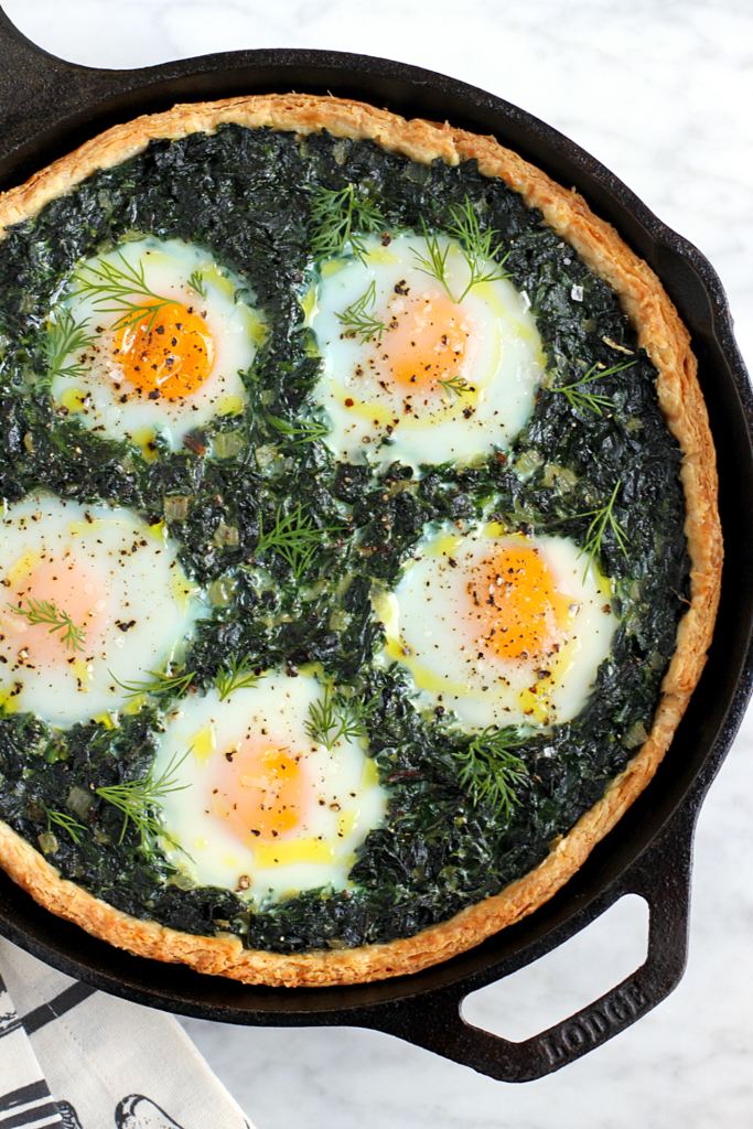 Close-up image of creamy greens pie with baked eggs.