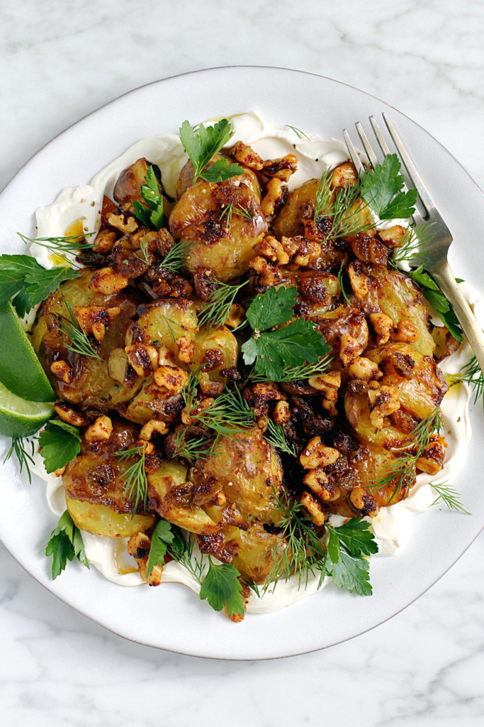 Close-up image of crispy smashed potatoes with walnut dressing.