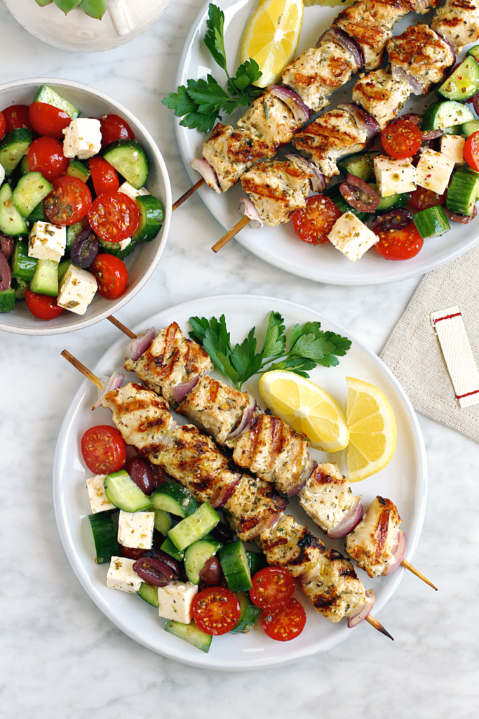 Image of grilled Greek chicken kebabs with cucumber, tomato and Feta salad. 